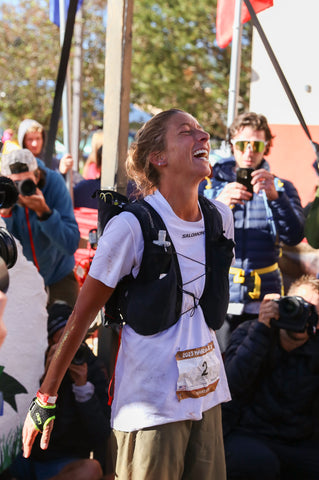 Courtney Dauwalter stands in front of the Hardrock at the finsih with her arms back with an expression of joy and relief