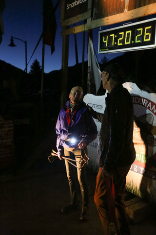 Pam Reed stands next to the rock after finishing the Hardrock 100 and talks to a staff member